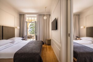 A hotel room with two beds, a TV, and a view of the outdoors.