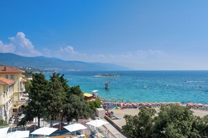 Ein Hotel an der Küste mit Blick auf das Meer, Strandstühlen und einem Rettungsturm.