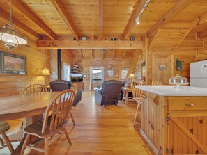 A wooden cabin interior with a dining area, sofa, and kitchen.