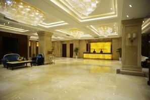 Un hall d’hôtel comprenant un comptoir d’accueil, un espace salon et des lustres.