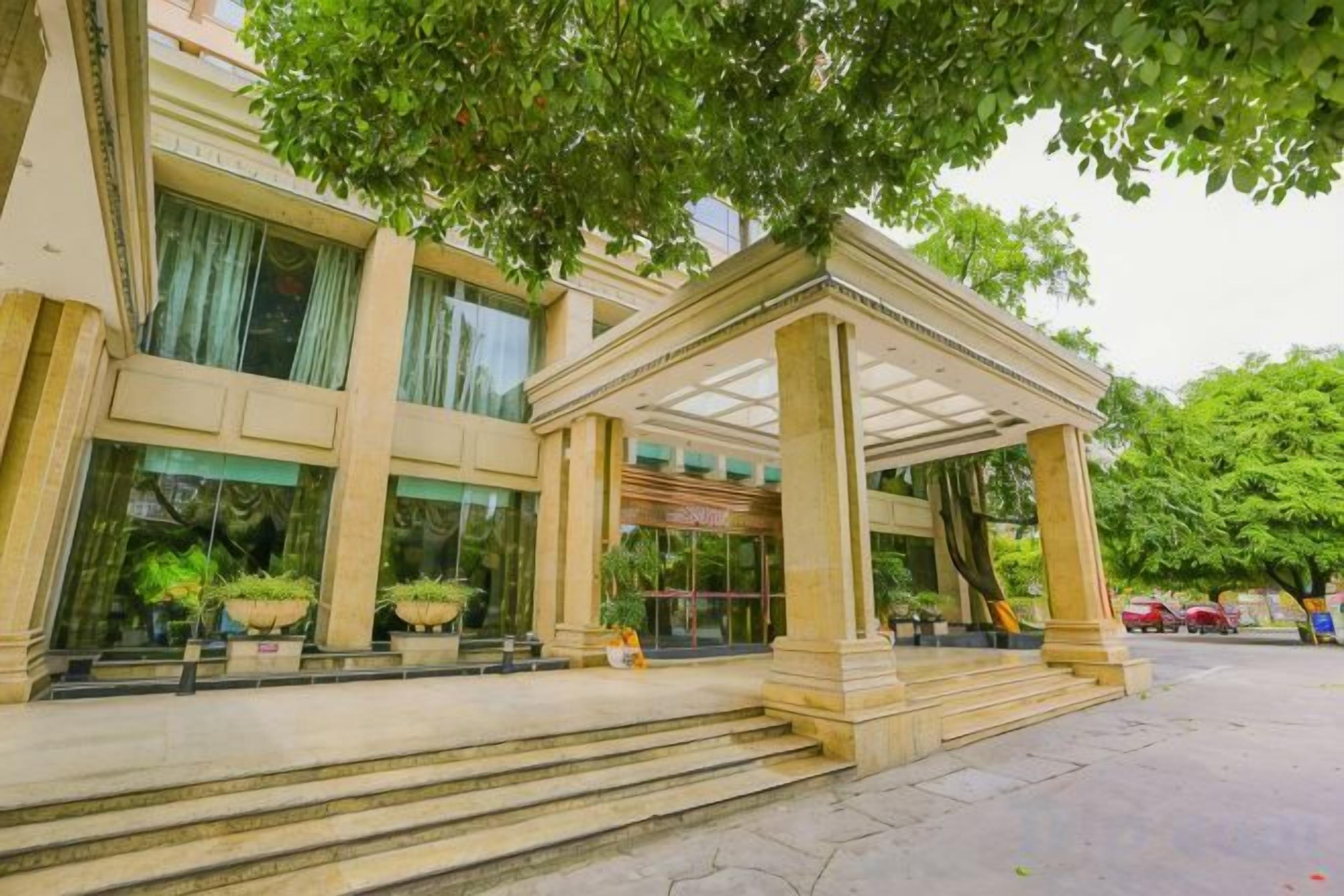 Ein Hotel mit Hauseingang, einer überdachten Veranda und Stufen, flankiert von Pflanzkübeln.