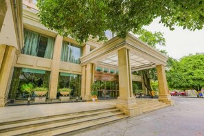 L’entrée d’un hôtel, avec un porche abrité, des marches menant à l’entrée et des plantes en pot.