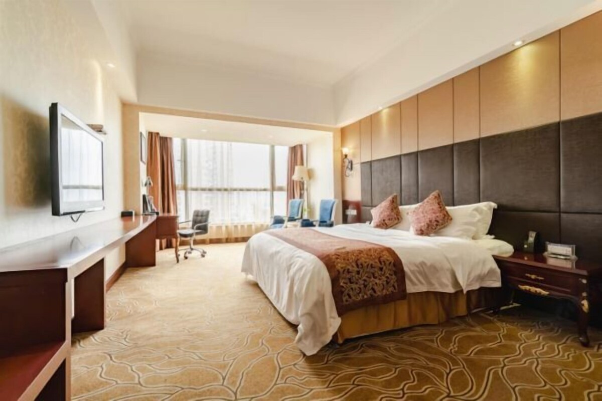 Une chambre d’hôtel avec un grand lit, un bureau, une télévision et une vue sur l’extérieur.
