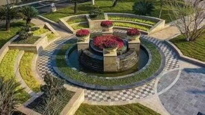 Een aangelegde tuin met een centraal, rond waterpartij, omringd door geometrische paden en diverse beplanting.