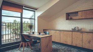 A modern kitchen with a wooden countertop, a dining area with a table and chairs, and a large window with a view of the outside. - Railway Apartments (Vilnius)