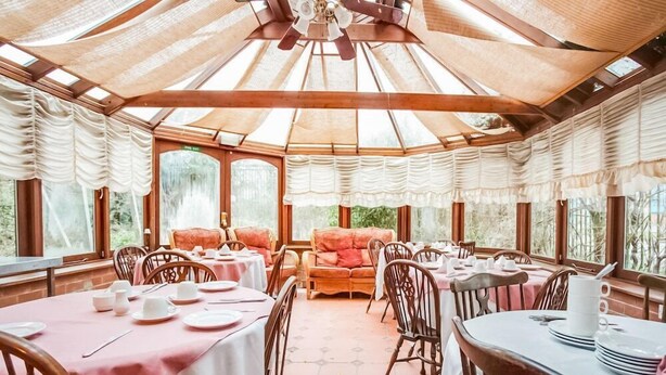 Un espace repas avec des tables rondes, des chaises et un coin salon central agrémenté d’un canapé.