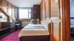 Une chambre d’hôtel comprenant un lit, un bureau, une chaise, une fenêtre et un lambris en bois.