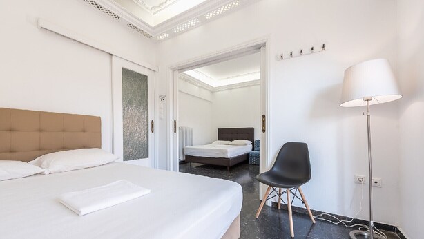 A hotel room with a large bed, a chair, and a floor lamp. - Acropolis View dream apartment (Athina)