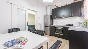 A compact kitchen with a dining area, featuring a refrigerator, oven, and a small island with a sink. - Acropolis View dream apartment (Athina)