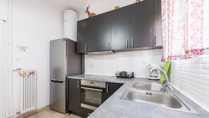 A compact kitchen with dark cabinets, a stainless steel refrigerator, an oven, a sink, and a coffee maker. - Acropolis View dream apartment (Athina)