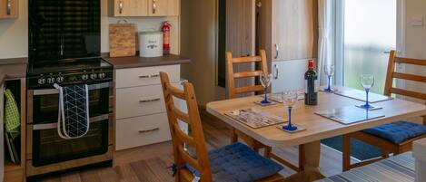 A compact kitchen with a stove, cabinets, and a dining area with chairs and a table set for two.