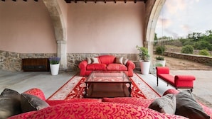 Un espace extérieur aménagé avec un ensemble de canapés rouges, une table basse et des plantes en pot.