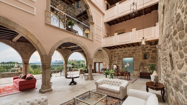 Un intérieur spacieux avec de hauts plafonds, des arches en pierre et un balcon donnant sur un paysage magnifique.