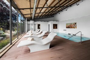 Un espace de bien-être doté d’une terrasse en bois, d’une piscine et offrant une vue sur l’extérieur.