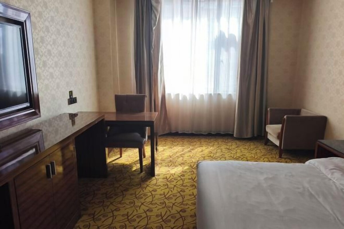 Una habitación de hotel con cama, escritorio, silla y televisión.