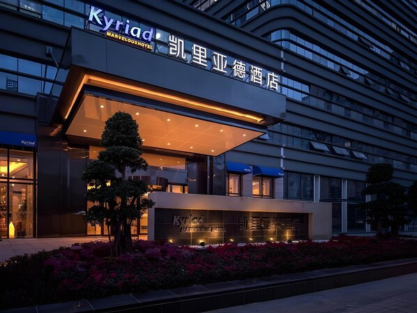 A hotel with a modern facade, signage in multiple languages, and a well-maintained garden area. - Kyriad Hotel Chengdu Wuhou NEW City (Chengdu)