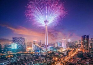 Un paisaje urbano con una torre destacada y fuegos artificiales.