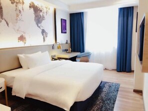 A hotel room with a large bed, a desk, a chair, a desk lamp, a world map on the wall, and a TV. - Kyriad Hotel Chengdu Wuhou NEW City (Chengdu)