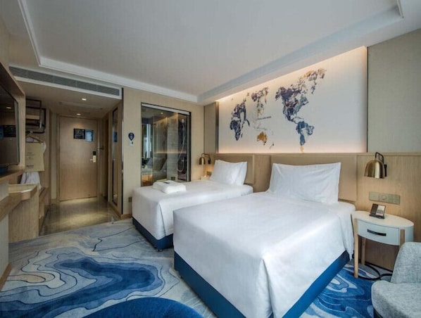 A hotel room with two beds, a large abstract wall art, a small bedside table, and a chair. - Kyriad Hotel Dongguan Shijie Daxin Jiangbin New City (Dongguan)