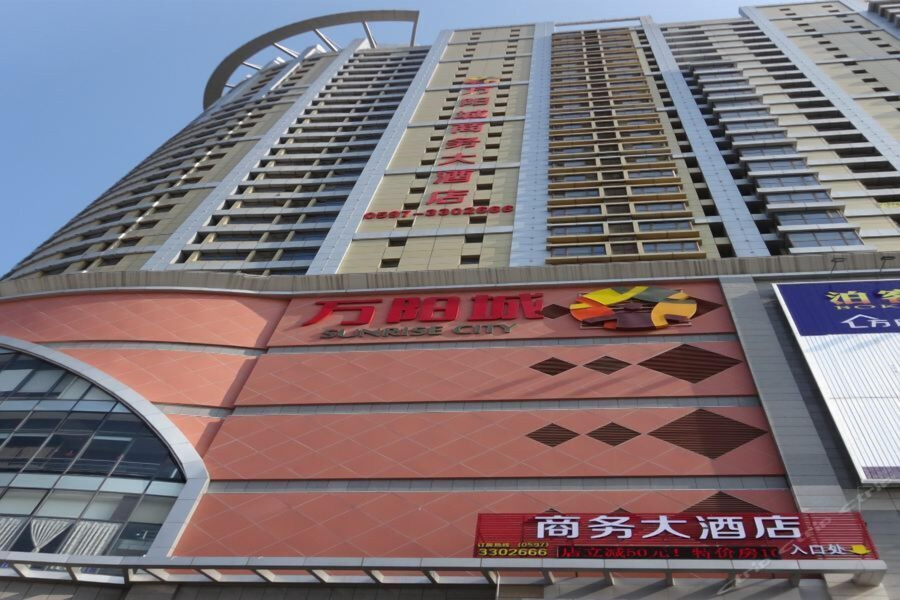 A tall hotel building with multiple floors, a prominent sign for Sunrise City, and a large advertisement for a business hotel.