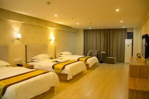Une chambre d’hôtel avec trois lits, un bureau, une chaise et un téléviseur.