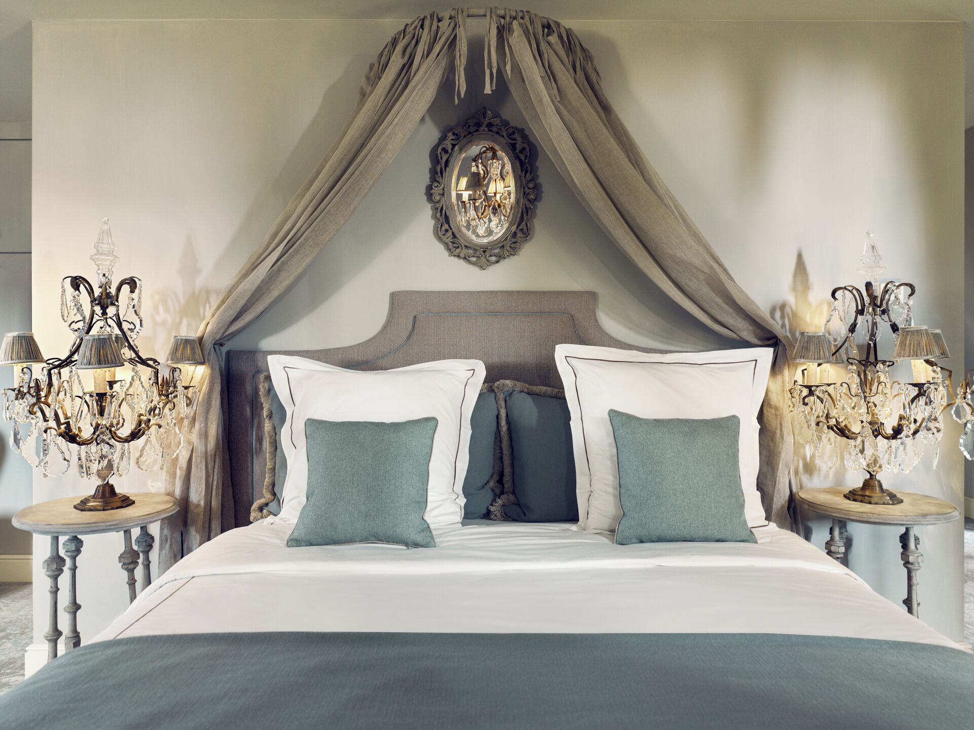 Une chambre à coucher avec un lit à baldaquin, deux tables de chevet avec des lampes et un miroir décoratif au-dessus du lit.