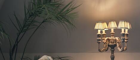 A chair with a blanket, a lamp, and a plant in a room with a patterned carpet.