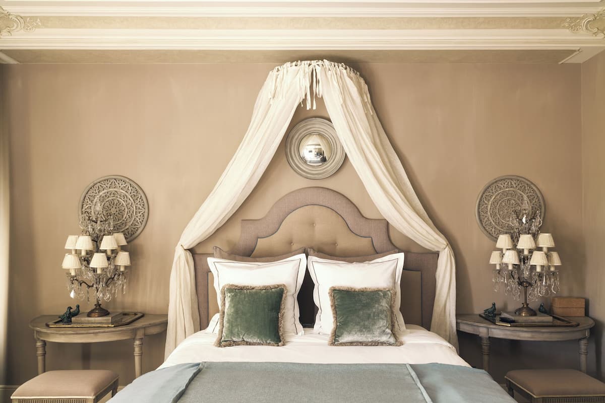 A bedroom with a canopy bed, two bedside tables with lamps, and decorative wall plates.