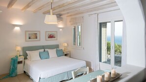 A bedroom with a bed, bedside tables, a window with a view, and a table with candles. - Exquisite "Villa Luna" with Pool & Jacuzzi close to the amazing Lia beach! (Mykonos)