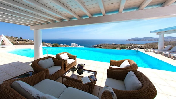 A covered outdoor area with a pool and wicker furniture, overlooking a scenic view of the sea. - Exquisite "Villa Luna" with Pool & Jacuzzi close to the amazing Lia beach! (Mykonos)