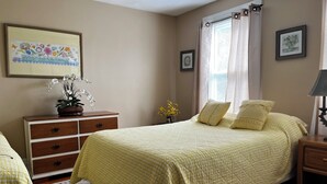 A bedroom with a bed, a dresser, a nightstand, a lamp, and a window with curtains. - Spacious Apt. 2 car free parking great location. (Cambridge)