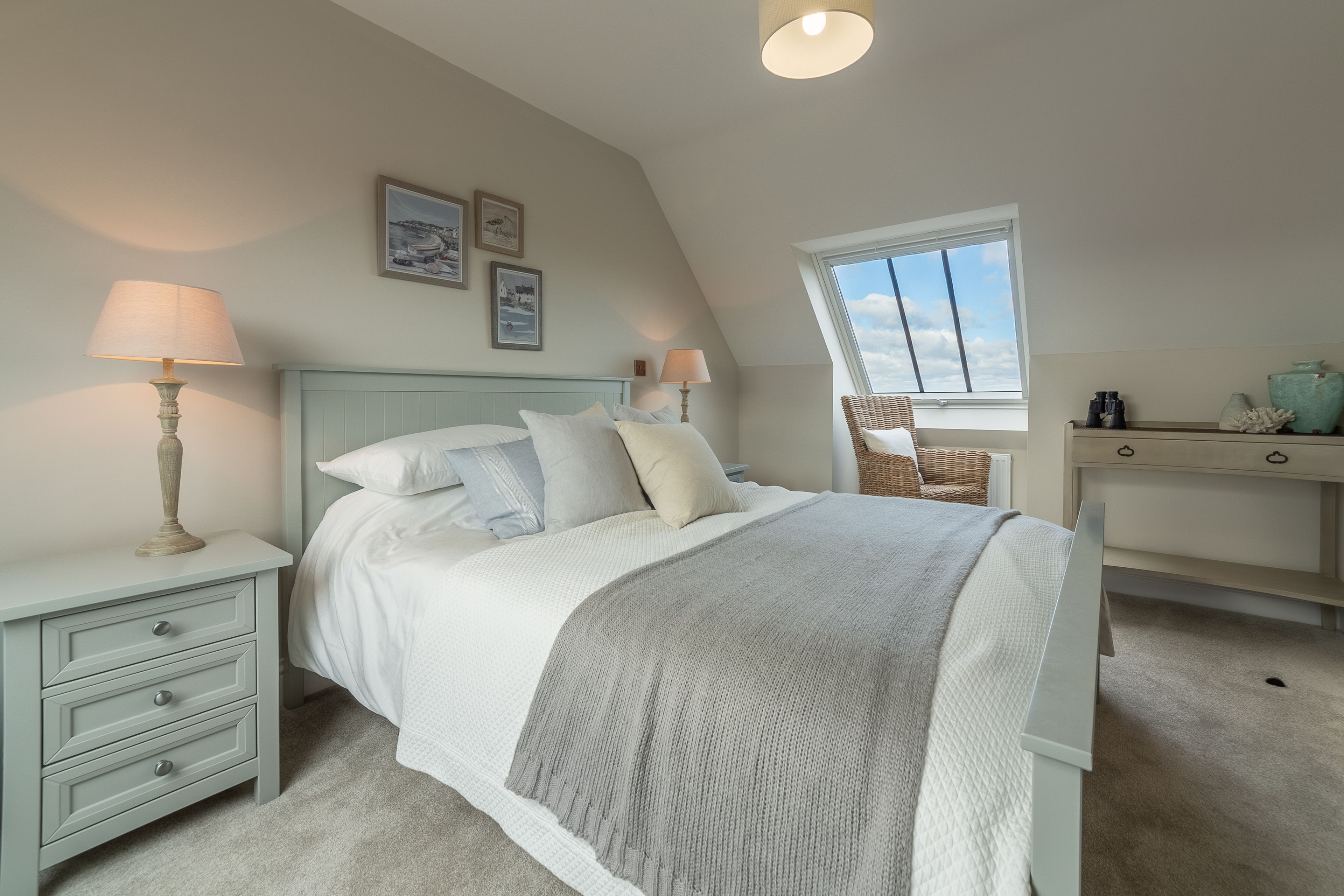 A bedroom with a bed, nightstands, a dresser, and a window.