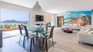 En moderne stue med et glasbord, en hvid sofa og et muralmaleri af et landskab.