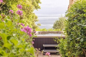 Un bain à remous entouré d’une végétation luxuriante, avec vue sur une étendue d’eau.