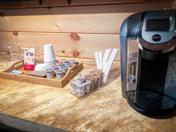 Una cafetera y una bandeja con tazas de café, una bolsa de café Starbucks y servilletas.
