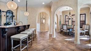 A spacious kitchen with a marble countertop, a bar area with stools, and a dining area with a chandelier.
