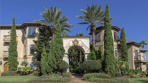 A grand building with an ornate entrance, tall cypress trees, and well-maintained gardens.