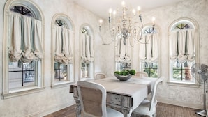 Un comedor con candelabro, mesa blanca y sillas.