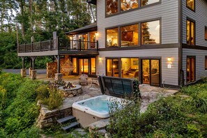 A two-story house with a balcony, a hot tub, and a stone fire pit.