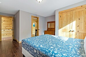 A bedroom with a bed, wooden wardrobe, and a mirror.