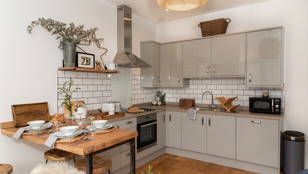 A modern kitchen with white cabinets, a wooden countertop, and a built-in oven.
