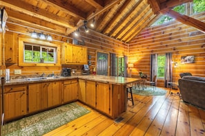 A wooden cabin with a kitchen, dining area, and a large window.