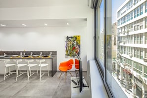 Enjoy a city view from the comfort of this stylish room, featuring a long dining table, vibrant artwork, and a large window.