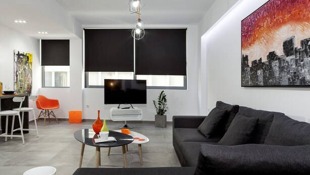 Ein modernes Wohnzimmer mit einer Couch, einem Couchtisch, einem Fernseher und einem Essbereich mit Stühlen und einem Tisch.