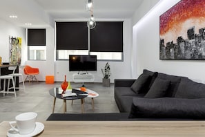 Una sala de estar moderna con un sofá, una mesa de centro, un televisor y un comedor con sillas y una mesa.