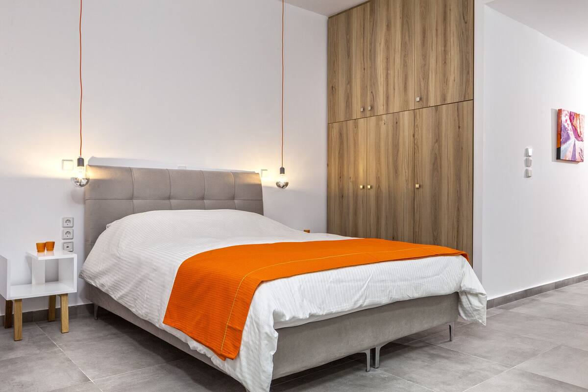 A modern bedroom with a bed, bedside table, and a wardrobe.