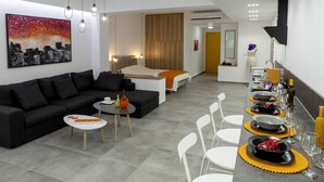 Ein modernes Hotelzimmer mit Wohnbereich, Essbereich und Schlafzimmer.