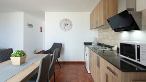 Una cocina moderna con armarios de madera, microondas integrado y un reloj de pared.