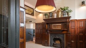 Un intérieur de style traditionnel, avec une cheminée, des boiseries et une lampe suspendue.