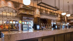 Un espace bar doté d’un comptoir en granit, de plusieurs robinets à bière et d’un réfrigérateur à vin.
